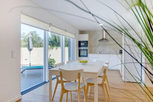 a kitchen and dining room with a white table and chairs at Casa D'Areia a 1 km da Praia. in Vila Praia de Âncora