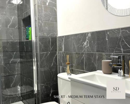a black tiled bathroom with a sink and a toilet at Ling Street - City Centre - Long stays - Contractors in Liverpool