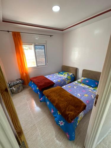 1 dormitorio con 2 camas y ventana en Apartement pret de la gare train, en Nador