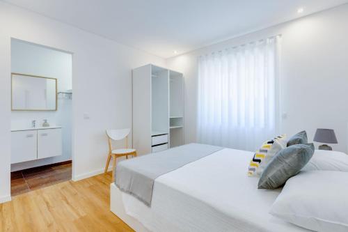 a white bedroom with a large bed and a bathroom at Casa D'Areia a 1 km da Praia. in Vila Praia de Âncora