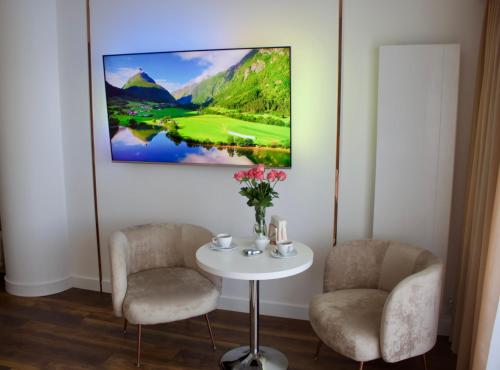 シュチェチンにあるHanza Tower -M&M Luxury Apartmentの椅子2脚とテーブル1脚と絵画1点が備わる部屋