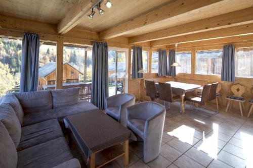 a living room with a couch and a table and chairs at Almdorf Stadl by ALPS RESORTS in Stadl an der Mur