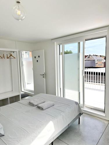 a white bedroom with a bed with two towels on it at Penthouse GuiZa in Namur