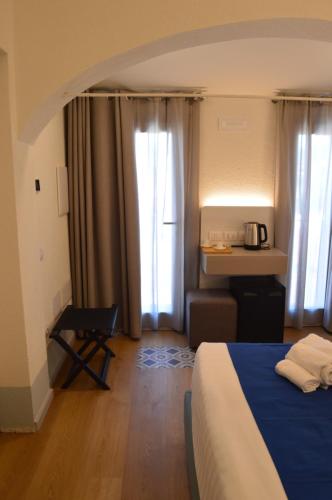 a hotel room with a bed and a chair and window at TANIT ROOMS & SPA in Villasimius