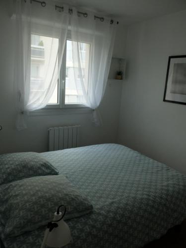 une chambre avec un lit et une fenêtre dans l'établissement T2 à 150 M du centre-ville, parking privé, à Vannes
