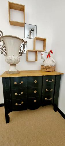 une commode noire avec un grand vase en haut dans l'établissement Au petit bonheur, à Carnoules