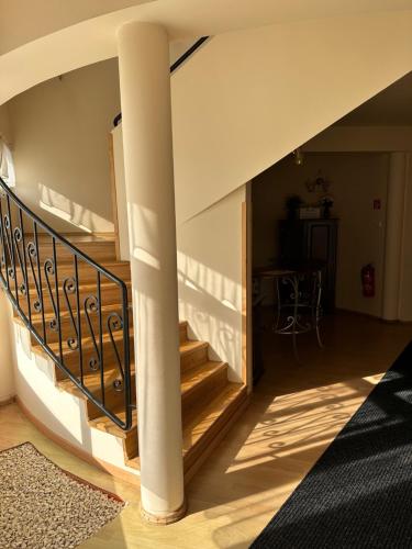 a spiral staircase in a house with a column at Cozy Garden Apartman in Gyula