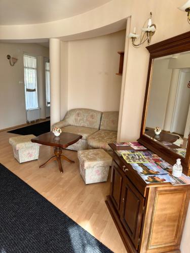 a living room with a couch and a mirror at Cozy Garden Apartman in Gyula