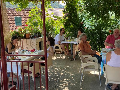 a group of people sitting at tables in a garden at Lotus House Dodoši in Dodoši