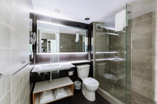 a bathroom with a toilet and a sink and a shower at Le Dauphin Montréal-Longueuil in Longueuil