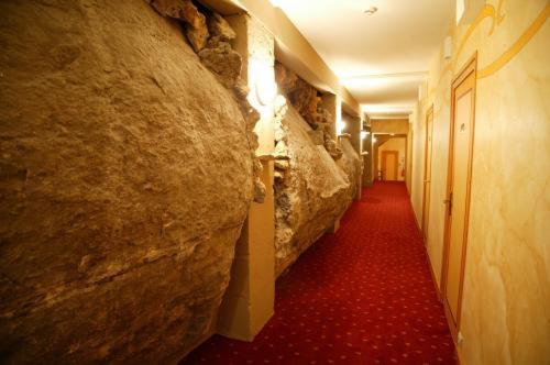 a hallway with a stone wall and a red carpet at Hôtel Le Cro-Magnon in Les Eyzies-de-Tayac