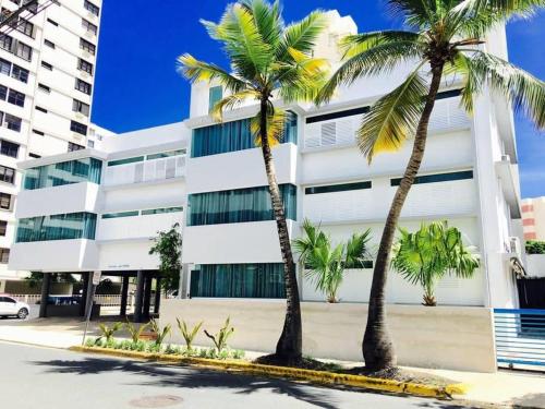 duas palmeiras em frente a um edifício em P0 - Walk To The Beach - 4br4br - 1113 Piccioni em San Juan