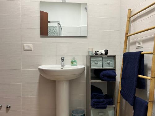 bagno con lavandino, specchio e asciugamani blu di La Dimora del Coach a L'Aquila