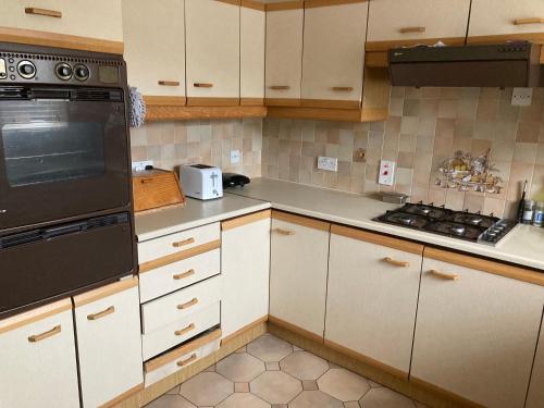 a kitchen with white cabinets and black appliances at Lokiladdich in Bearsden