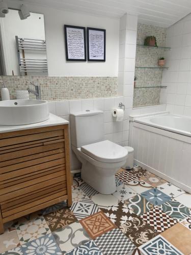 a bathroom with a toilet and a sink and a tub at Seaglass Cottage Mumbles in Oystermouth