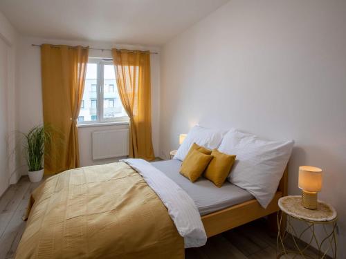 a bed with yellow and white pillows and a window at Apartmán Zlatá stoka in České Budějovice