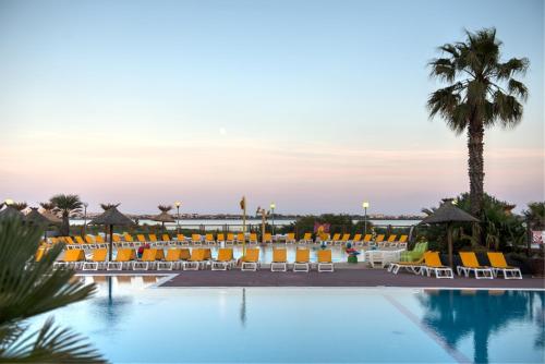 a hotel pool with chairs and a palm tree at BT - Le Soleia, confort & lumière, 2 ch, 2 sdb, entre mer et Petite Camargue, super équipé in Lattes