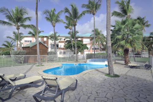 a swimming pool with two chairs and palm trees at Magnifique appt Crystal Beach in Saint-François
