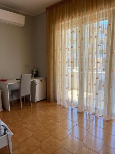a room with a table and a window with curtains at Le Stanze di Lucia vicino Ospedale Cardinale Panico a Tricase in Tricase