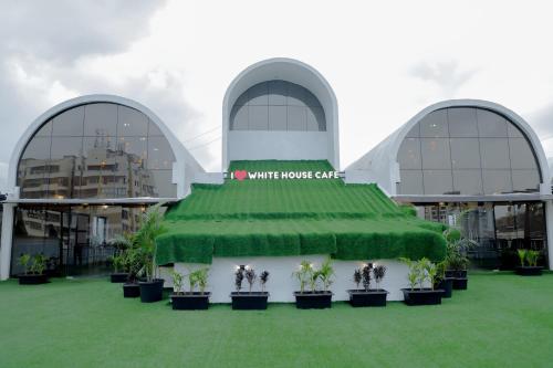 a white house cafe with a green canopy in front of a building at Hotel Royal Accord in Surat