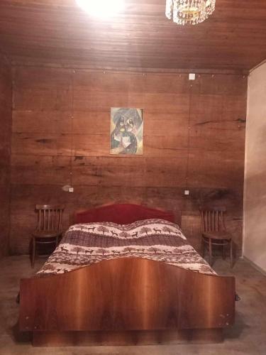 1 dormitorio con 1 cama con pared de madera en Rusikos guest house, en Oni