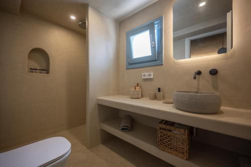 uma casa de banho com um lavatório, um WC e um espelho. em Tholaki luxury home em Kamari