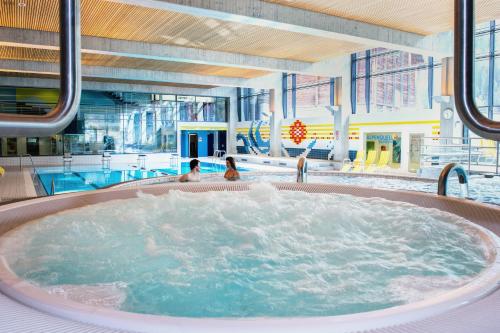 una bañera de hidromasaje en una piscina con 2 personas en Soliva Hotel & Apartments en Samnaun