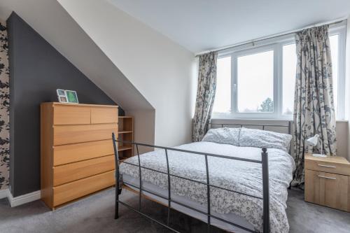 a bedroom with a bed and a dresser and a window at Homestay near Roundhay Park, North Leeds in Leeds