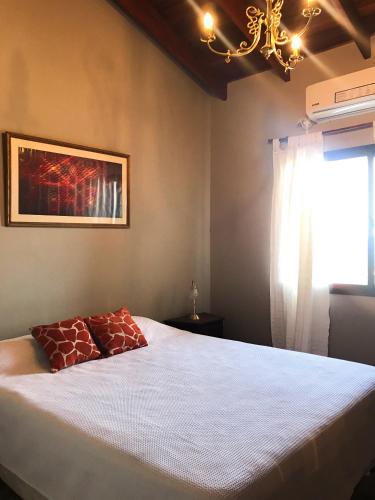 a bedroom with a bed with a chandelier and a window at Hermosa casa con vista al lago in Villa Carlos Paz