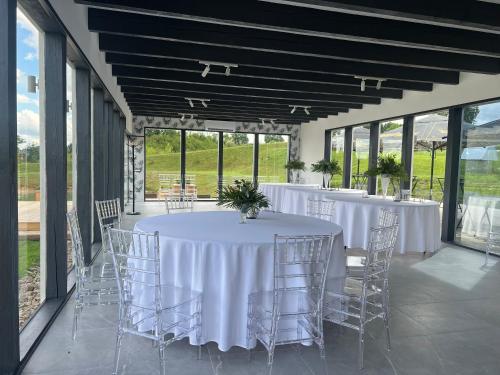 stolik z białymi stołami i krzesłami w pokoju z oknami w obiekcie Sodyba “Pas Pransku” w mieście Telsze