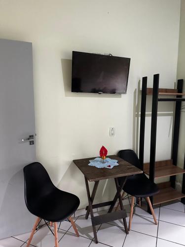 a dining room table with two chairs and a television on a wall at Pousada Meraki Beach in Caraguatatuba