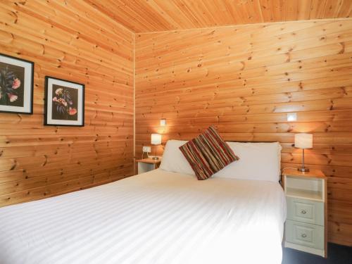 um quarto com uma cama e paredes de madeira em Elm Lodge em Keswick