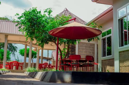 a patio with red chairs and an umbrella at Randa Cottages Moshi in Kirua