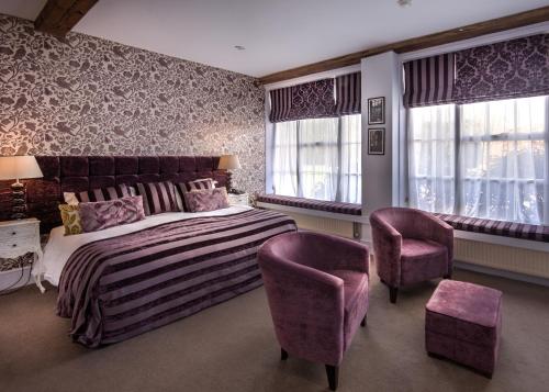 a bedroom with a bed and two purple chairs at Hintlesham Hall Hotel in Ipswich