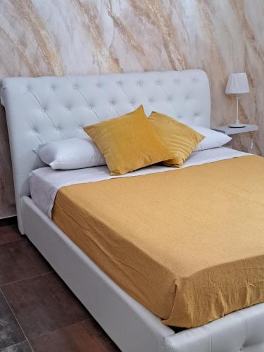 un letto bianco con lenzuola e cuscini gialli di Star suite ☆ a Catania