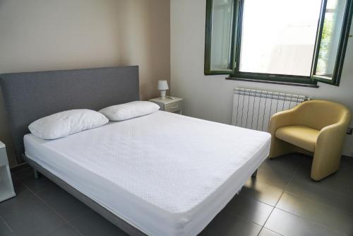 Villetta San Martino في Torraca: غرفة نوم بسرير ابيض وكرسي اصفر