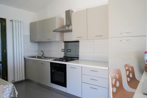a kitchen with white cabinets and a stove top oven at Villetta San Martino in Torraca