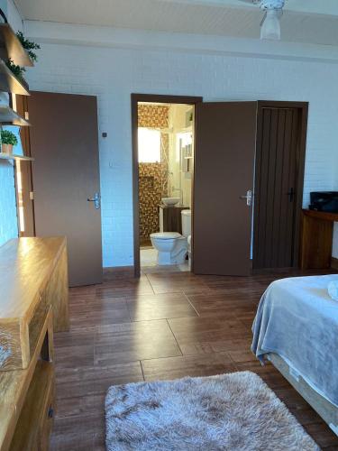 a bedroom with a bed and a bathroom with a toilet at Casa do Point in Saquarema