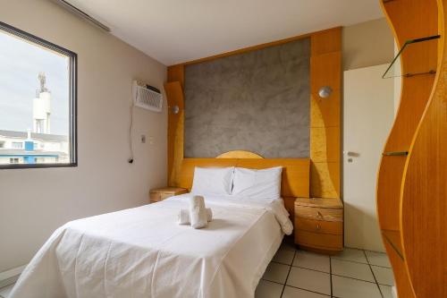 um quarto com uma cama com lençóis brancos e uma janela em Apto com sacada a poucos metros da praia VIN202 em Florianópolis