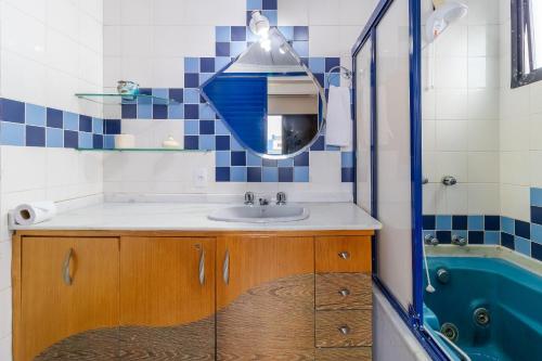 uma casa de banho com um lavatório, um espelho e uma banheira em Apto com sacada a poucos metros da praia VIN202 em Florianópolis