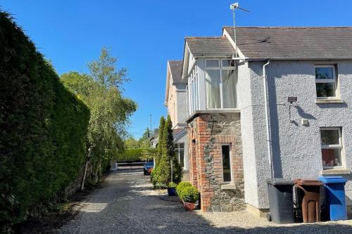 a stone house with a driveway in front of it at Converted Victorian Coach House on the North Coast in Coleraine