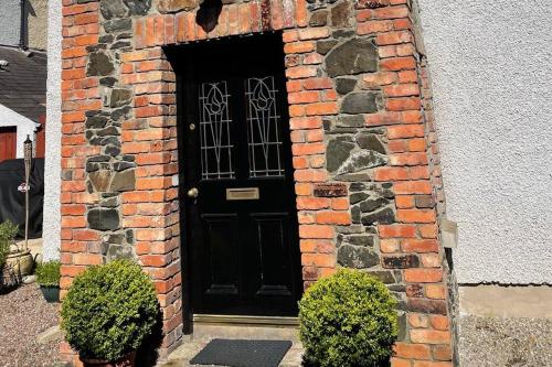 a brick building with a black door on it at Converted Victorian Coach House on the North Coast in Coleraine