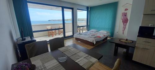 a room with a bed and a table with a view of the ocean at Azur Apartments in Sozopol