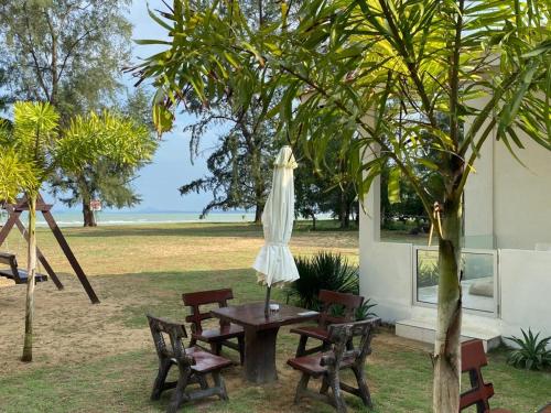 a table and chairs with an umbrella and a tree at DamaiiKu in Cherating