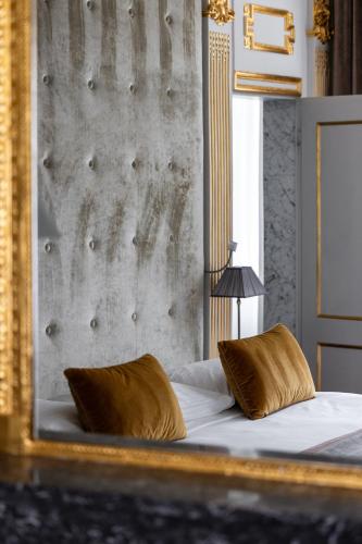 a bedroom with a bed with a mirror on it at Hotel Le Place d'Armes - Relais & Châteaux in Luxembourg