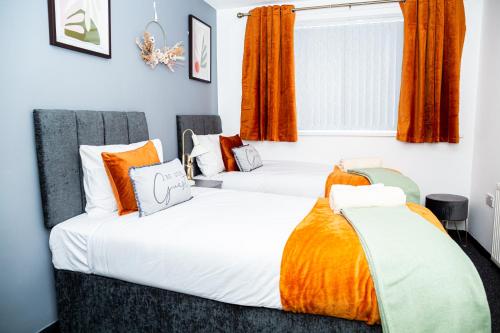 two beds in a room with orange curtains at Luxurious 3-Bed House in Dudley - DY1 in Dudley