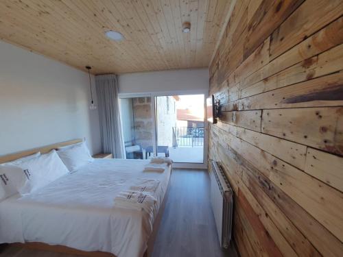 a bedroom with a large bed and a wooden wall at Casa da Marquinhas - Turismo Rural in Lama de Ouriço
