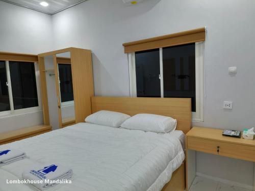 a bedroom with a bed and a desk and windows at Lombokhouse Mandalika in Kuta Lombok
