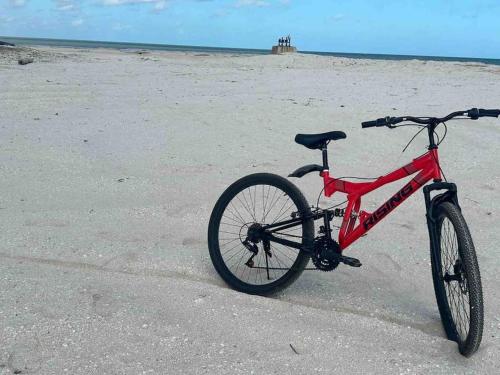 una bicicleta roja estacionada en la playa en Casa con arte, mar y alberca, en Telchac Puerto