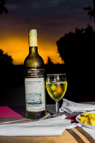 a bottle of wine and a glass on a table at Randa Cottages Moshi in Kirua